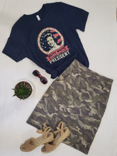 Load image into Gallery viewer, Image of knee length camo printed pencil skirt with pockets, paired with a Vote For Betty campaign graphic tee shirt. Sandels and sunglasses.